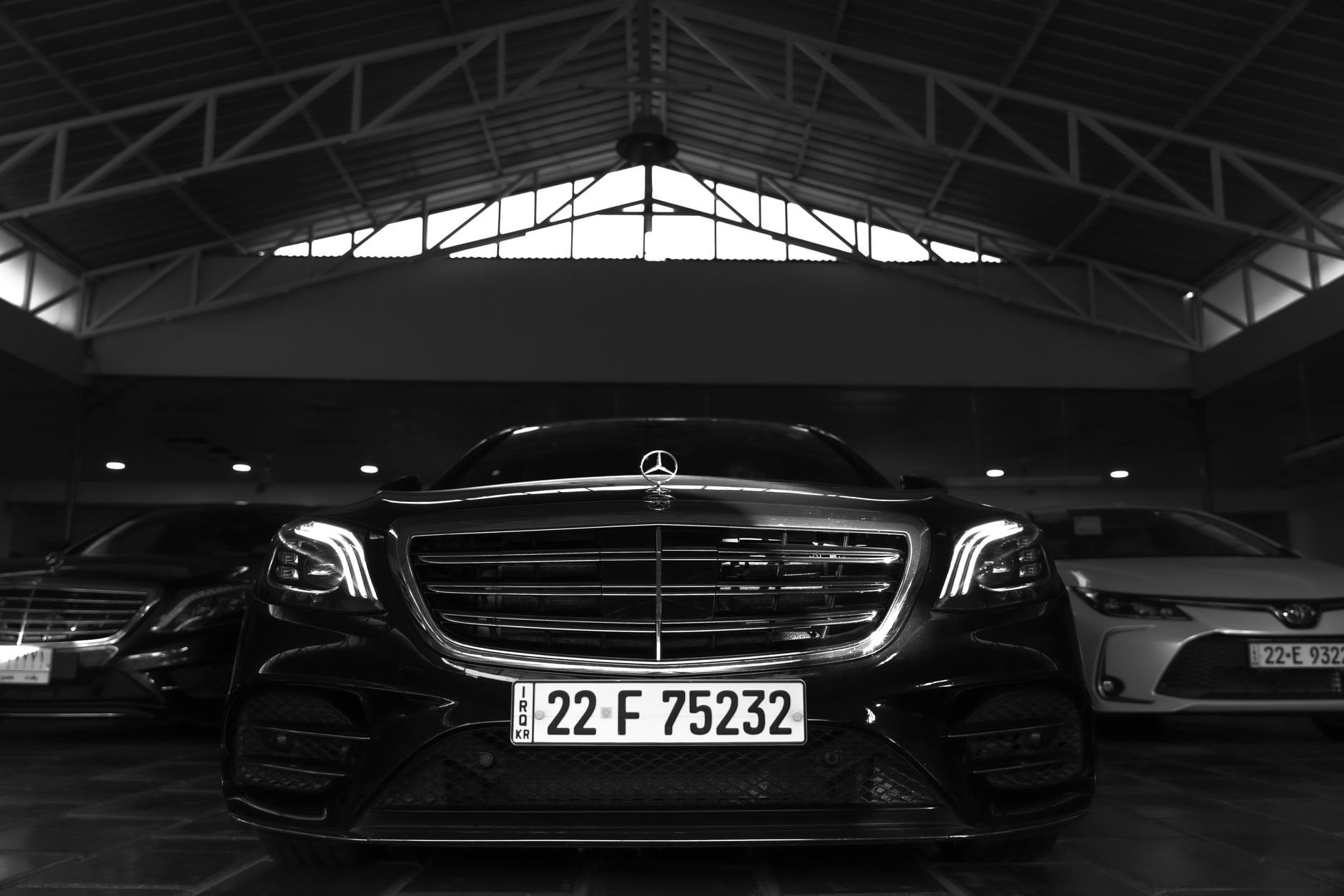 Black luxury car showcased in a modern showroom with sleek design and ambient lighting.
