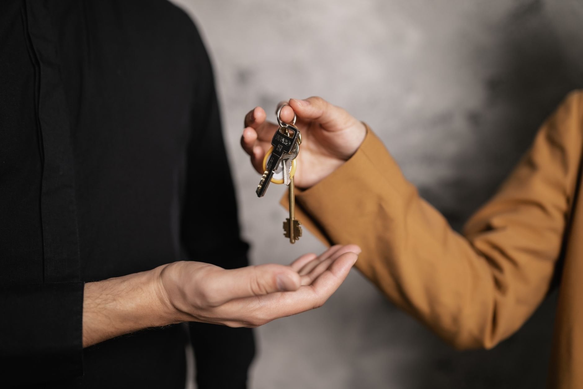 Close-up of one person handing over keys to another, symbolising a vehicle transaction.